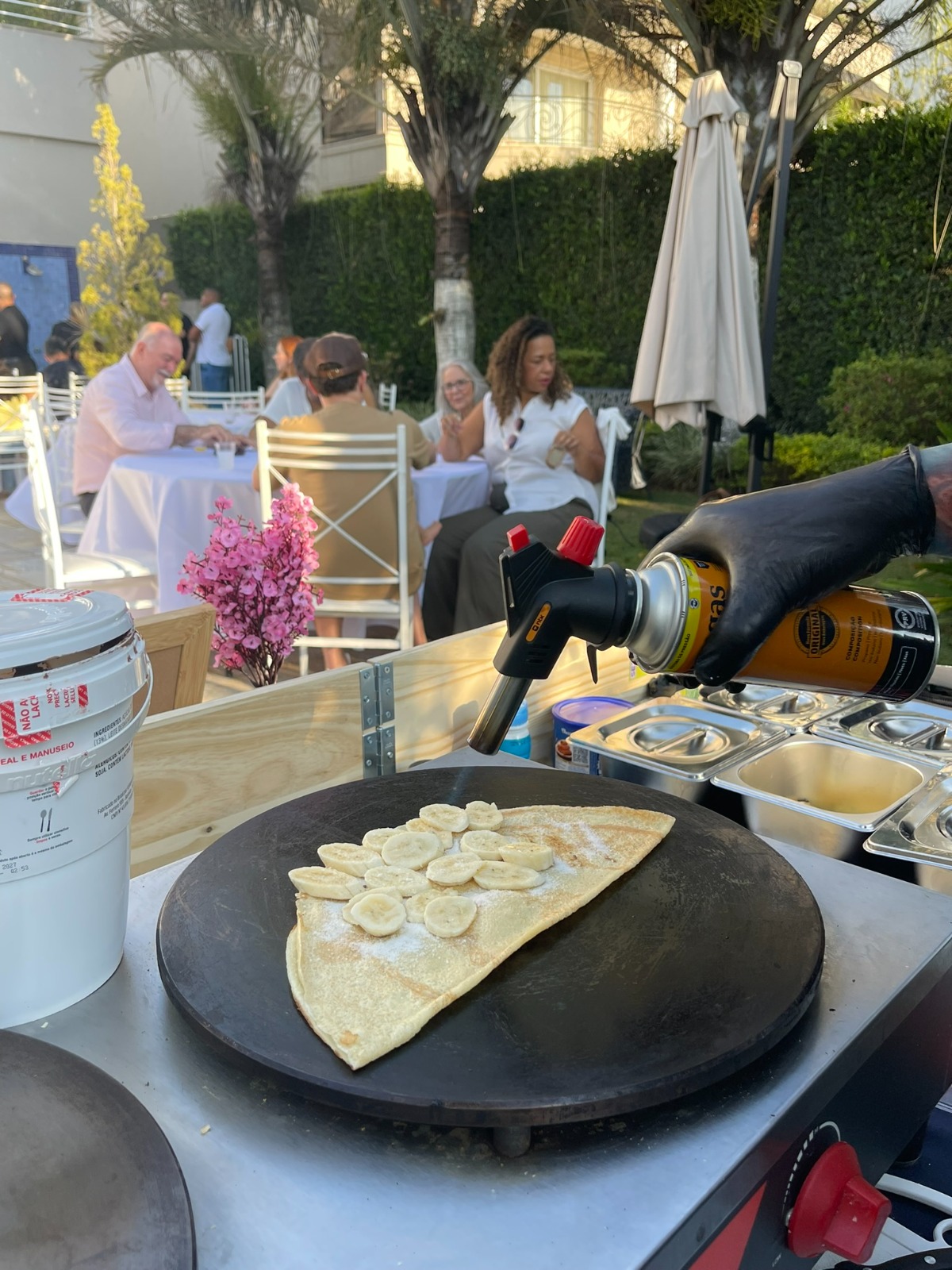 Crepe de banana sendo finalizado com maçarico ao ar livre