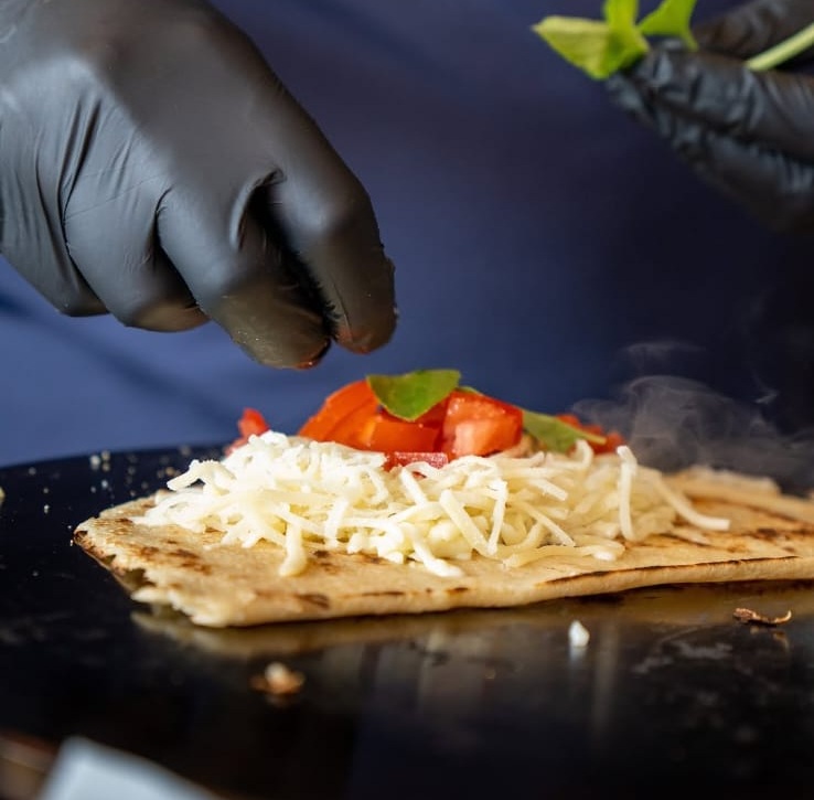 Crepe francês de queijo e tomate sendo montado na chapa