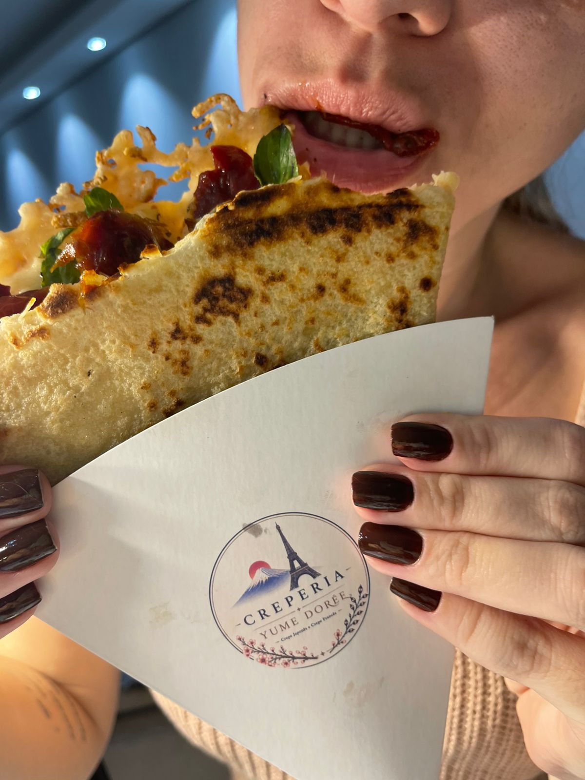 Convidada mordendo um crepe salgado com tomate seco